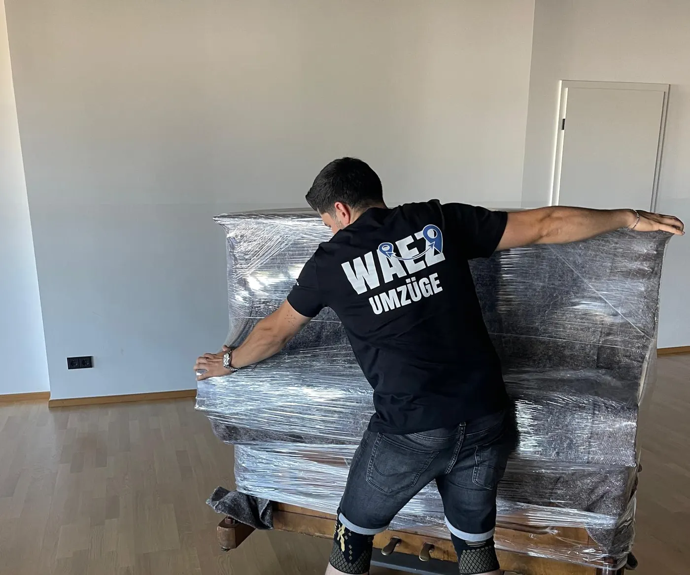 Mitarbeiter von WAEZ Umzüge polstert ein Klavier mit Decken und Stretchfolie