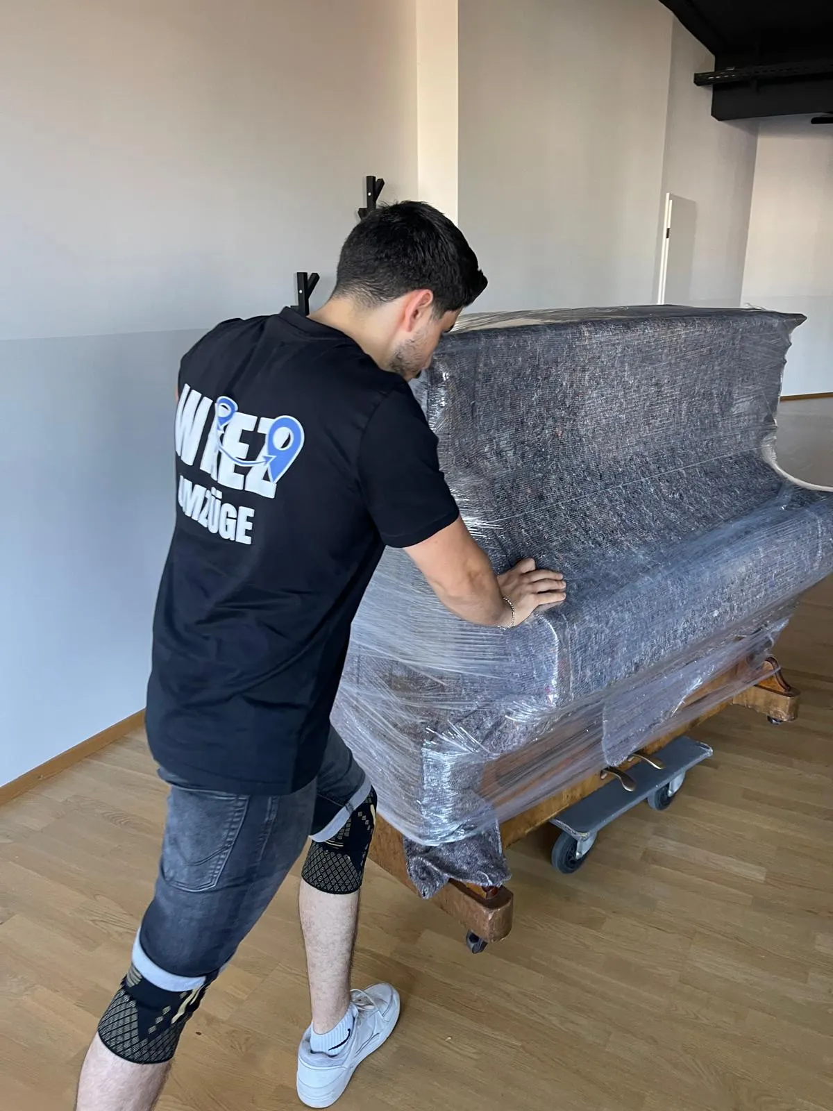 Verpacktes Klavier auf dem Klavierroller vor dem Abtransport